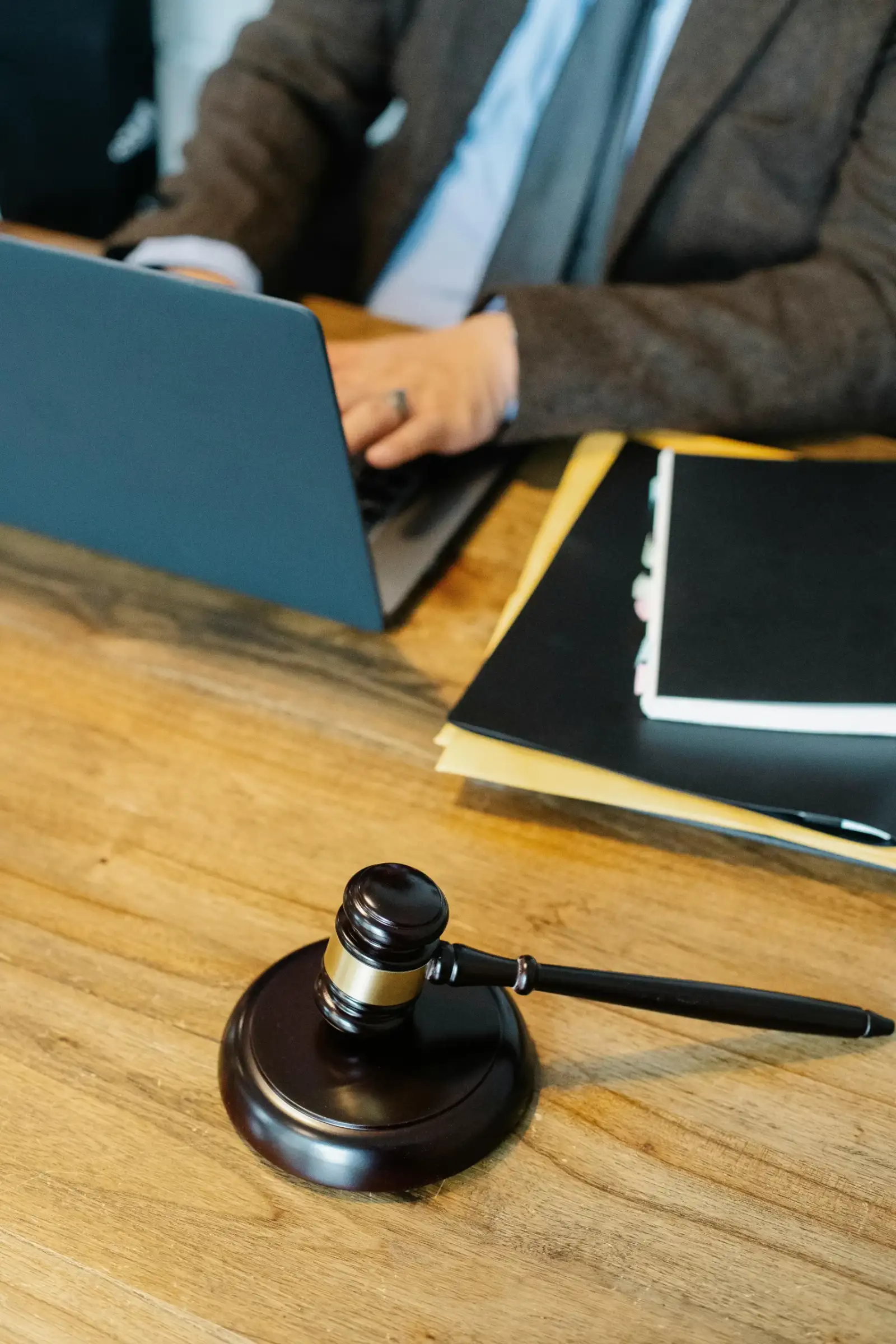 A gavel on a desk beside a laptop and a stack of document folders