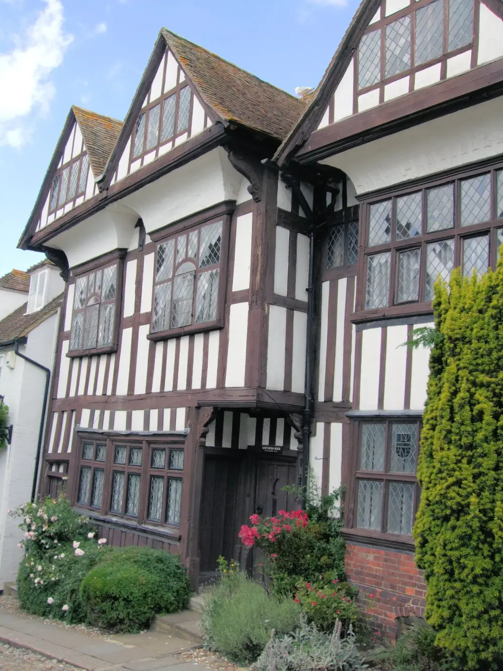 A timber-framed period house with leaded windows and a planted front garden