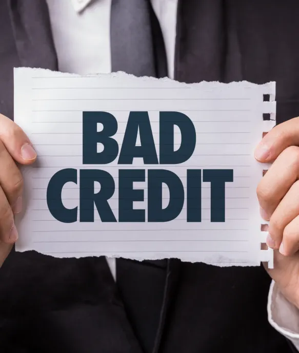 A person in a suit holding up a torn sheet of paper reading Bad Credit