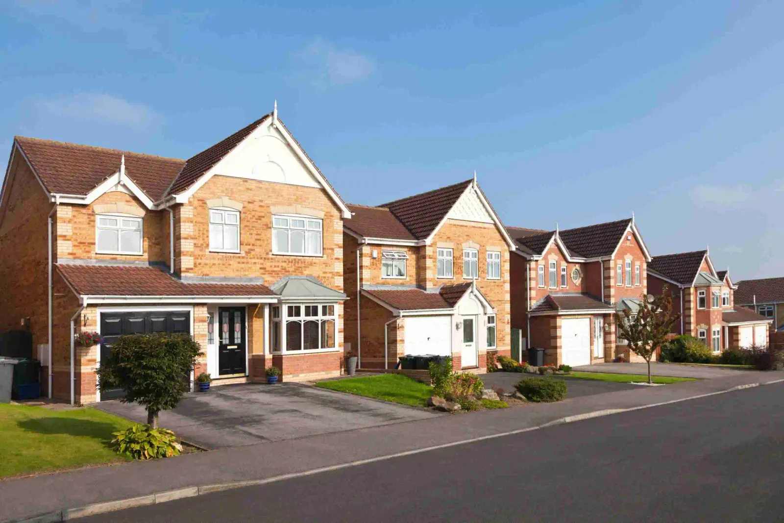 A row of modern detached brick houses on a quiet residential street