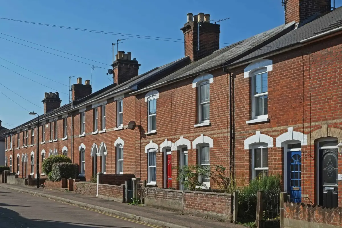 A row of red brick terraced houses along a residential street under a clear sky