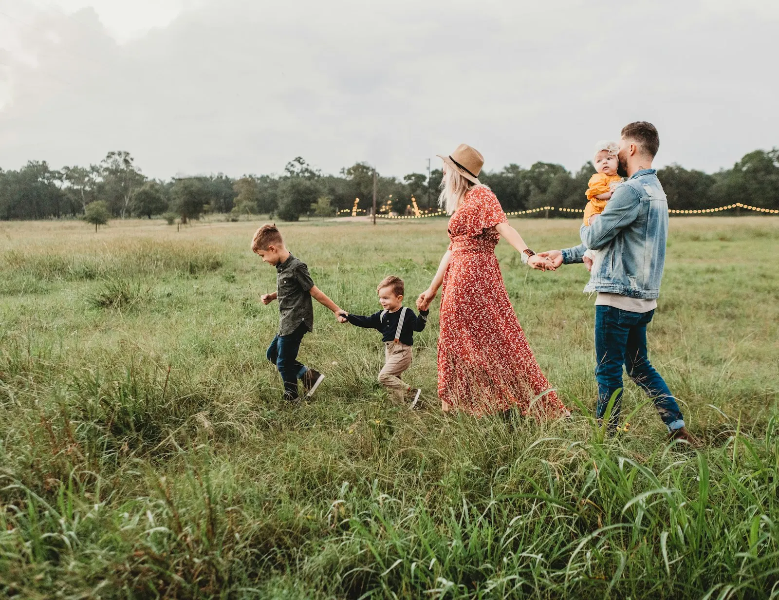 A family with young children walking together through a grass field