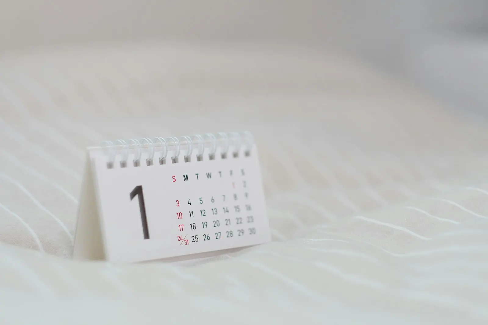 A small desk calendar standing on a pale surface